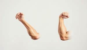 A pair of muscular arms demonstrating eccentric and concentric strength training techniques against a clean, minimalist background. In the foreground, the left arm performs a bicep curl with controlled eccentric motion, while the right arm completes the concentric contraction. The lighting is soft and directional, accentuating the definition of the muscles. The composition is balanced, with a neutral color palette and simple, uncluttered design to focus attention on the key differences between the two movement patterns.
