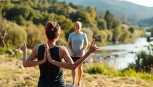 A serene outdoor scene, with a person engaged in gentle yoga or stretching exercises against the backdrop of a lush, riverside landscape. Warm, natural lighting casts a calming glow, accentuating the harmony between the individual's physical movements and the tranquil environment. In the middle ground, a therapist observes, their demeanor exuding compassion and a holistic, biopsychosocial approach to sports therapy. The scene conveys a sense of balance, where physical, psychological, and social elements seamlessly integrate to promote healing and well-being.