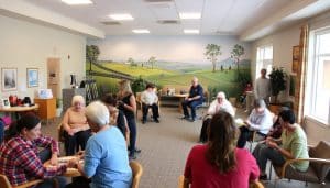 A community-based rehabilitation center in Calgary, with a warm, welcoming atmosphere. In the foreground, a group of people engaged in various therapeutic activities, such as group discussions, physical exercises, and arts and crafts. The middle ground features a bright, open-plan space with natural lighting, comfortable seating, and therapeutic equipment. In the background, a mural depicting scenes of nature and community, conveying a sense of tranquility and connection. The overall mood is one of support, empowerment, and a focus on holistic well-being. The image is captured with a wide-angle lens, emphasizing the collaborative and inclusive nature of the programs.